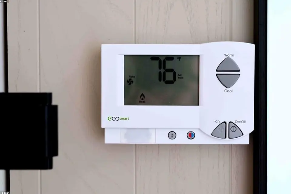 A digital thermostat on a white wall